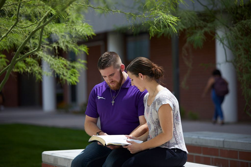 Students studying bible together outside.