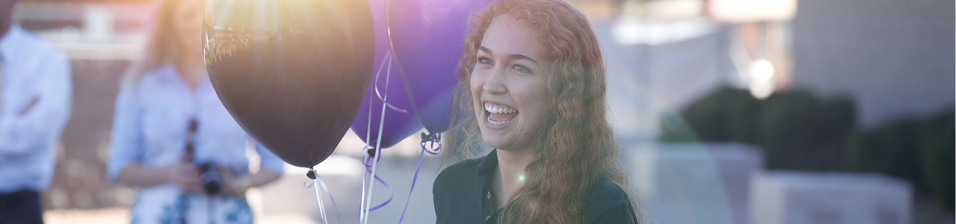 Girl smiling holding balloons