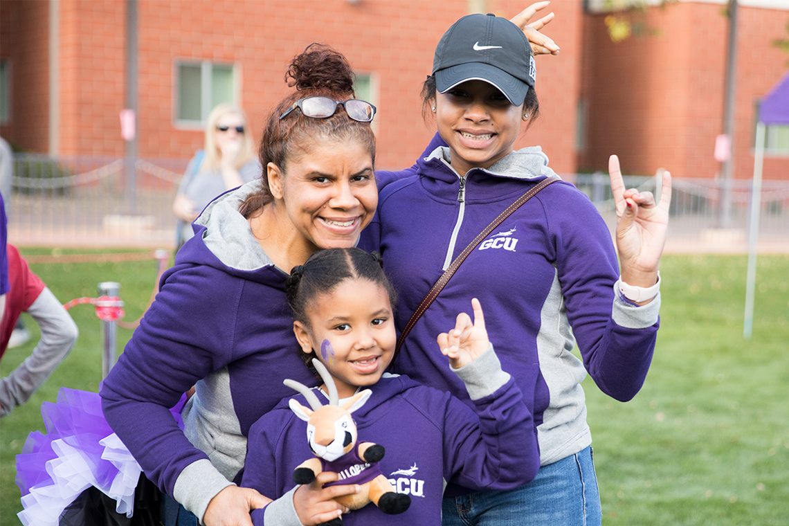 Mom and her daughters smiling outside wearing purple GCU garb.