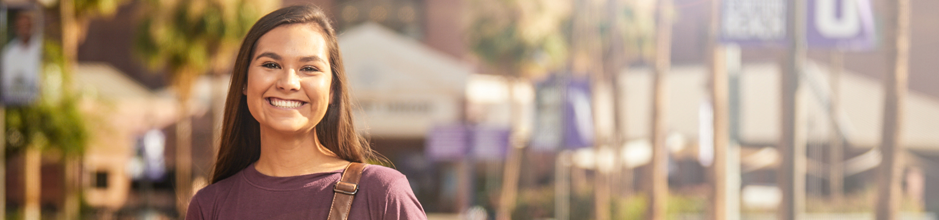 Student smiling in front of building on campus.